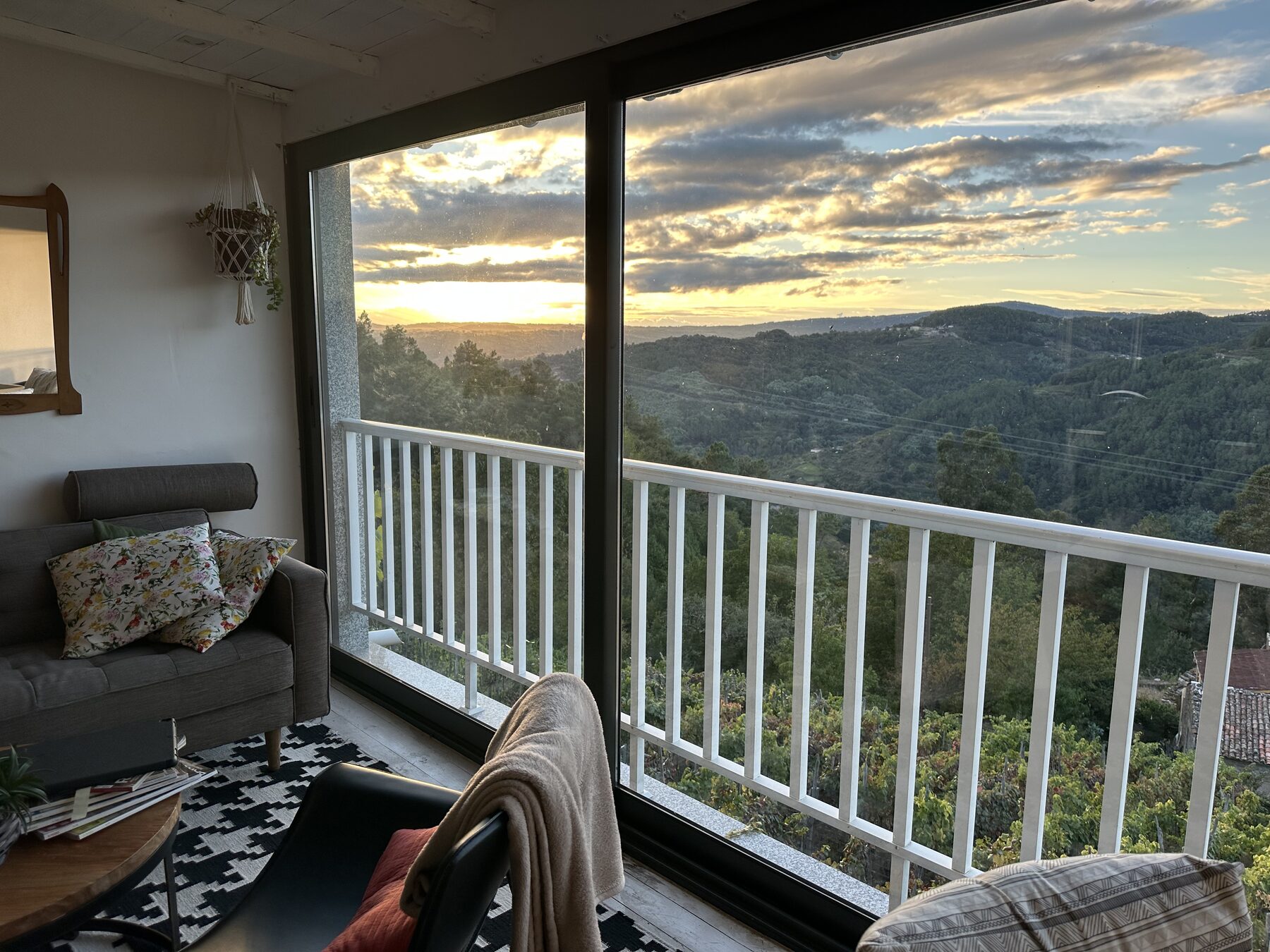 Open-plan living room of Casa da Viña with a large window onto the Miño valley at sunset