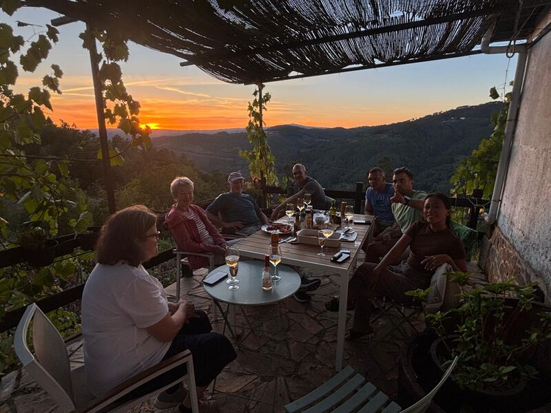 Guests sharing wine and dinner on the terrace of Casa da Viña at sunset over the Miño valley